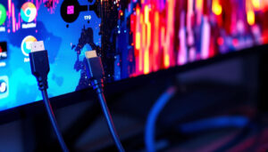 A photograph of a side-by-side comparison of a displayport 2.1 cable and an hdmi 2.1 cable connected to a high-resolution led display