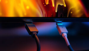 A photograph of a side-by-side comparison of a displayport 1.4 and hdmi 2.1 cable connected to a high-resolution led display